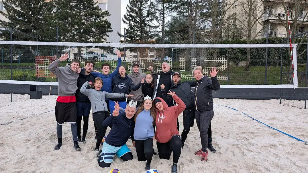 Groupe de joueurs de PESD beach-volley souriants et posant ensemble après avoir participé au tournoi de l'Épiphanie, sur les terrains de sable à Lyon Croix-Rousse.