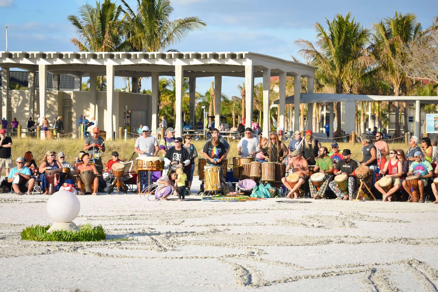 A large group of people enjoying a drum circle on Siesta Key Beach at sunset