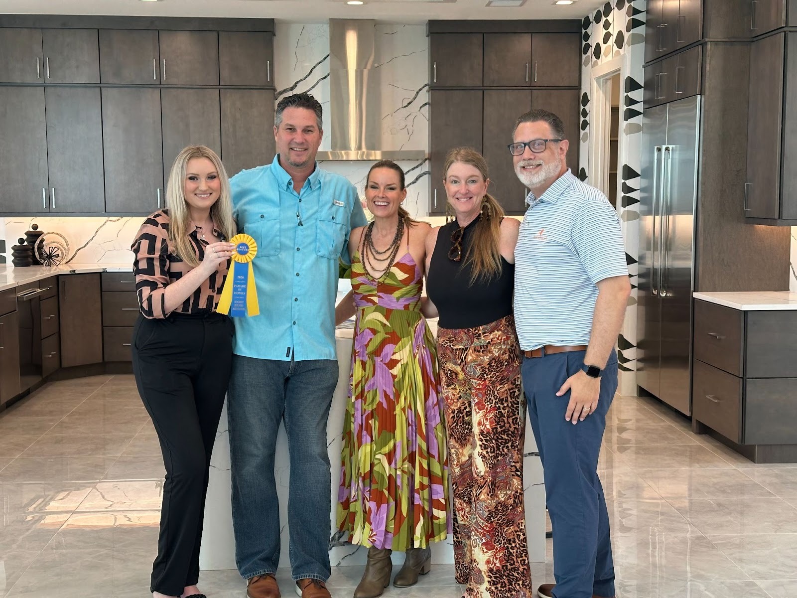 Medallion Home team and Parade of Homes judges posing with the Parade of Homes merit award in the kitchen of a Medallion model home.