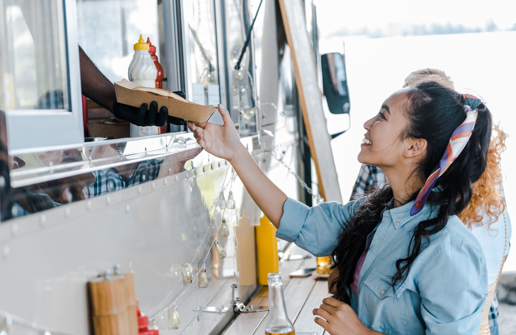 Man giving plate of food to woman from a food truck window.
