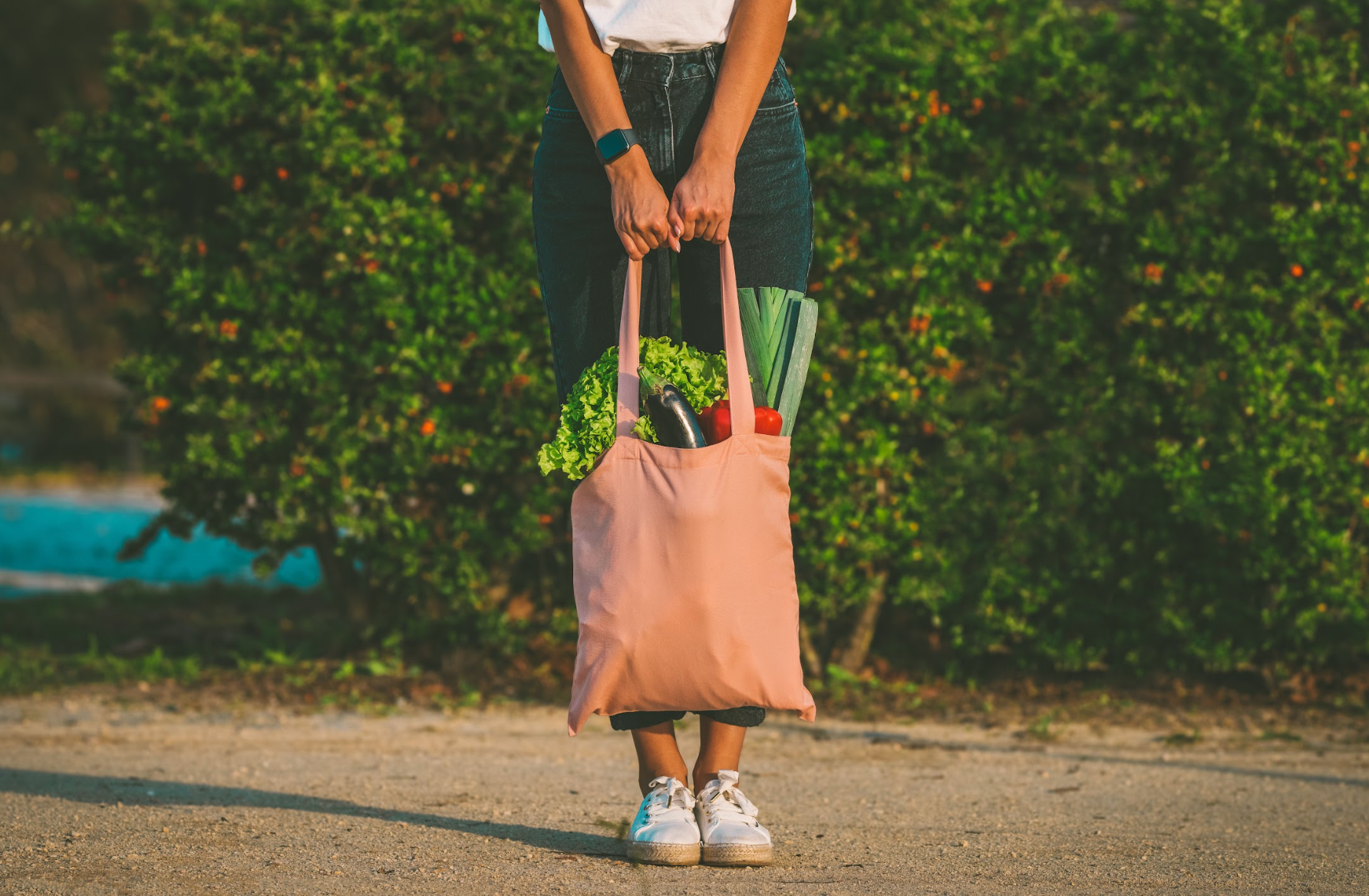 Woman with pink cotton reusable eco bag with fresh vegetables.