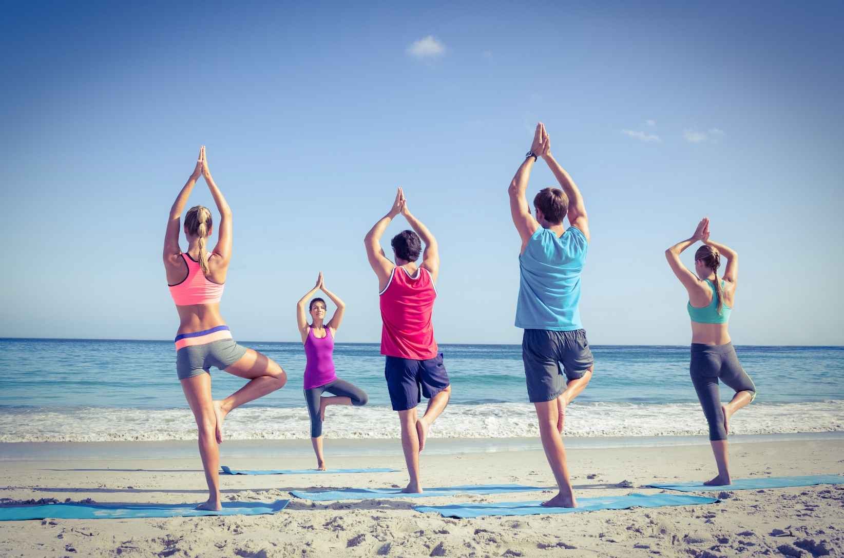 Group of people doing a yoga class on the beach