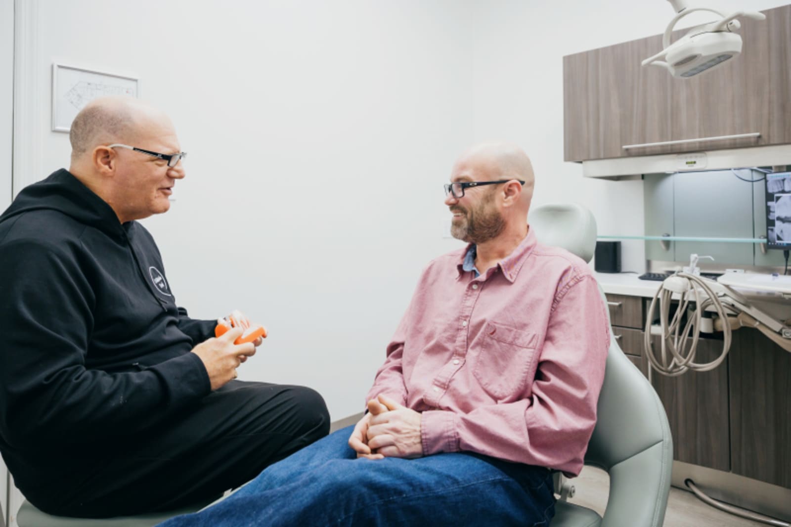 Male patient and dentist having relaxed conversation in clinical setting