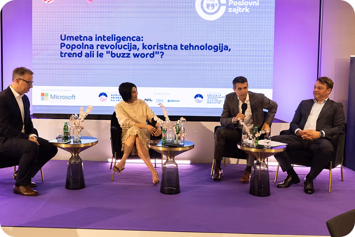 Four speakers seated on stage in a panel discussion about AI with a purple backdrop and text in Serbian.