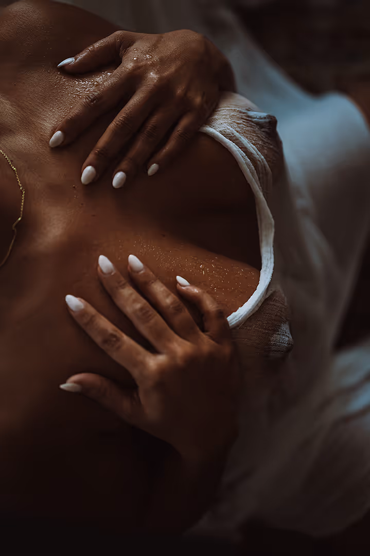 Close-up of two hands with white nails resting on a wet back wearing a white top.