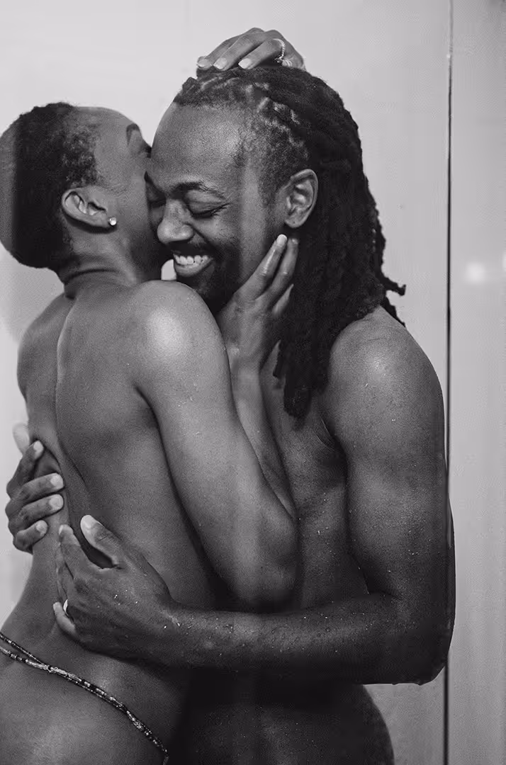 Black and white photo of a smiling couple embracing intimately, with the woman holding the man's head and the man holding her back.
