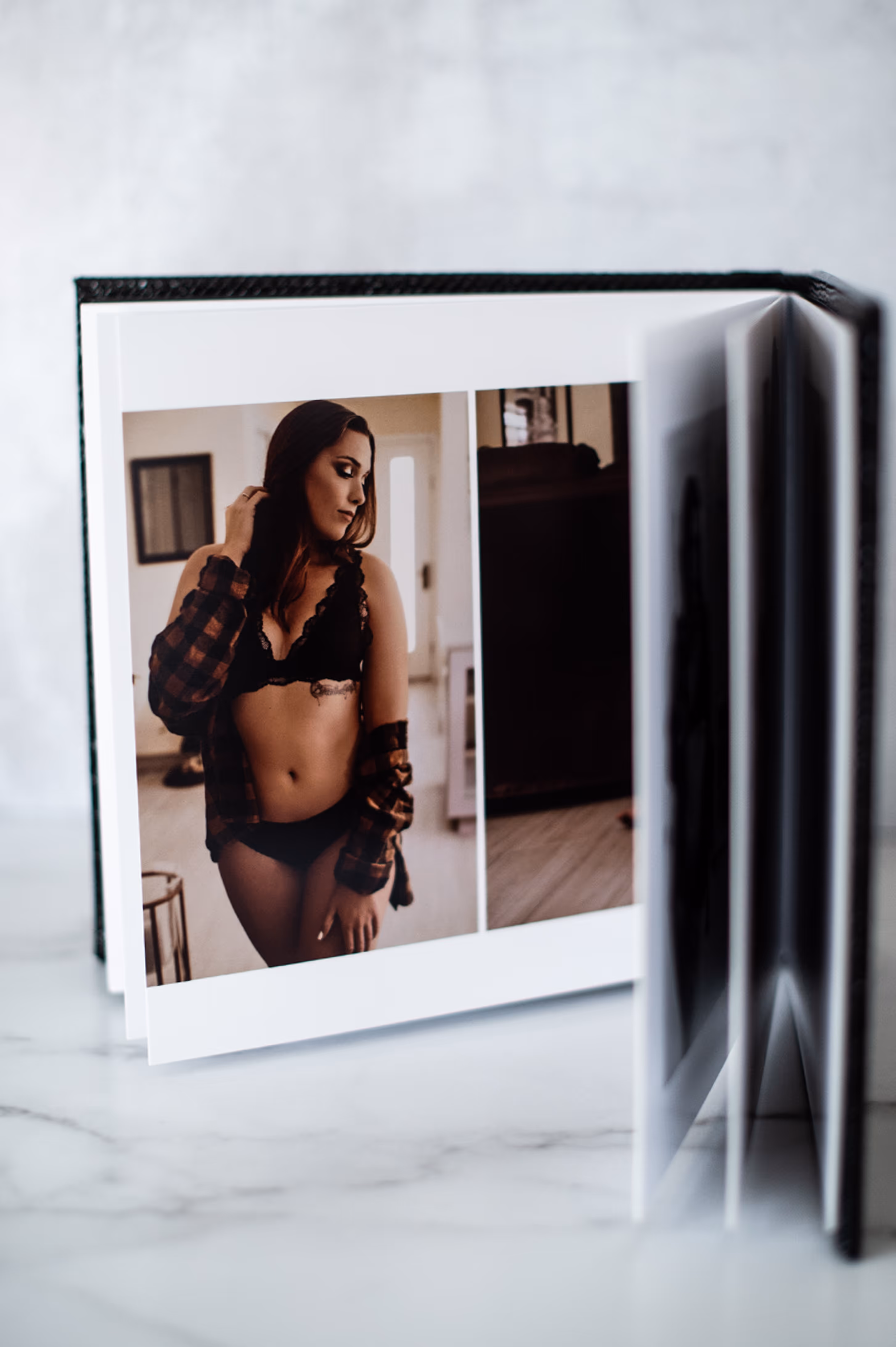 Open photo album displaying a photo of a woman in black lingerie and a plaid shirt indoors.