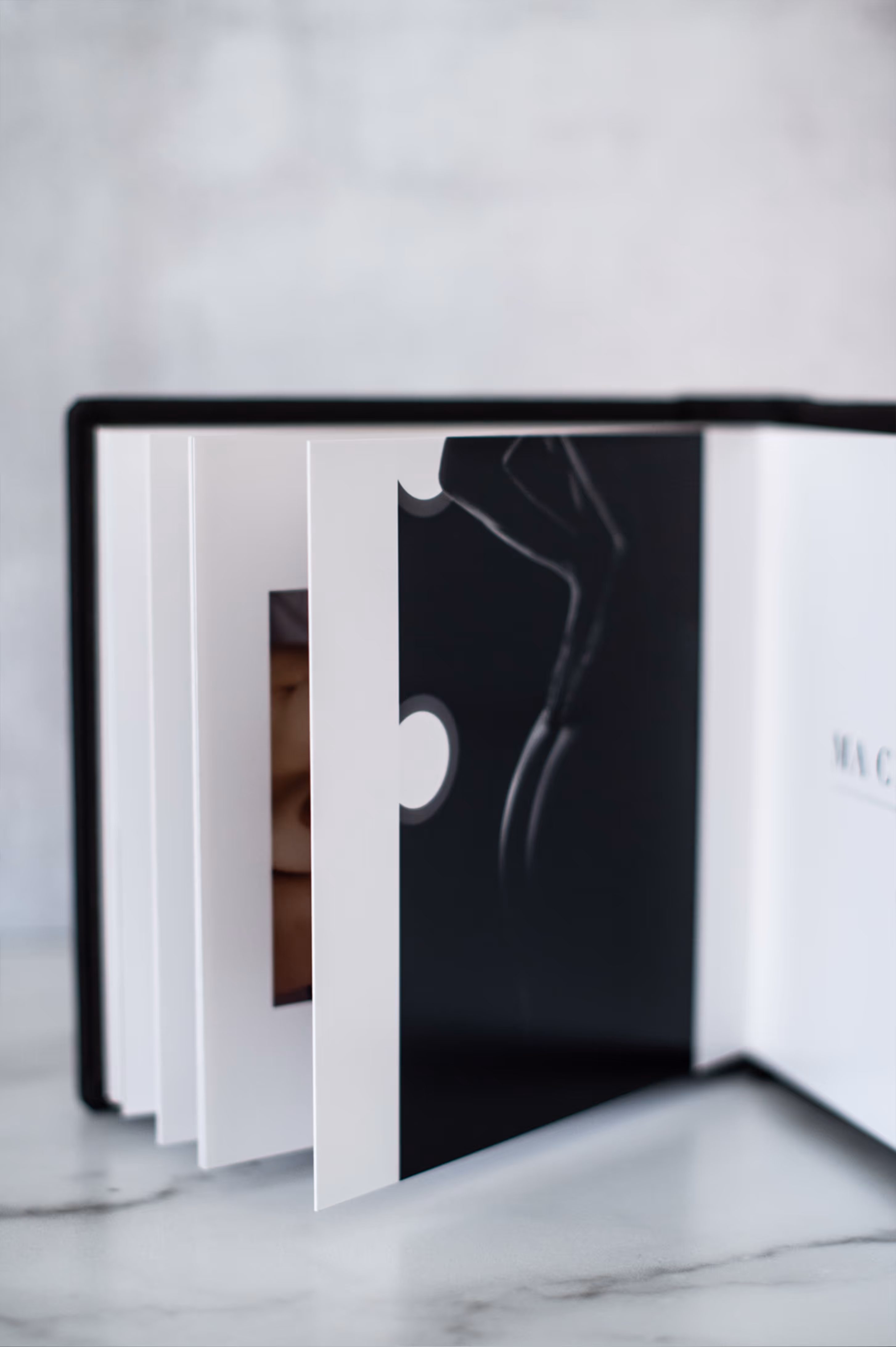 Open photo album with partially flipped pages showing a black and white image of a human silhouette.