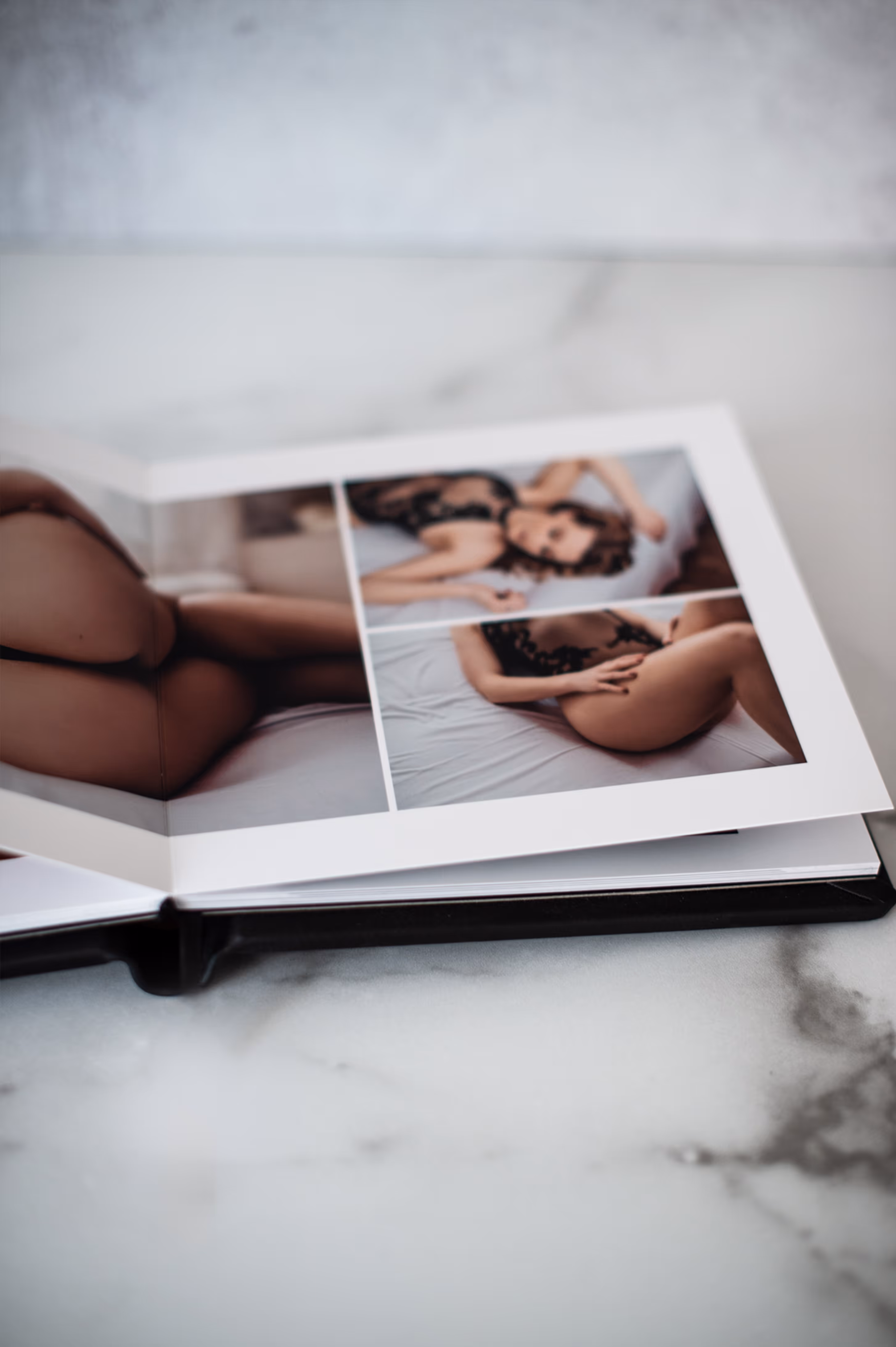 Open photo album on a marble surface showing a woman in black lingerie posing on a bed in three photos.