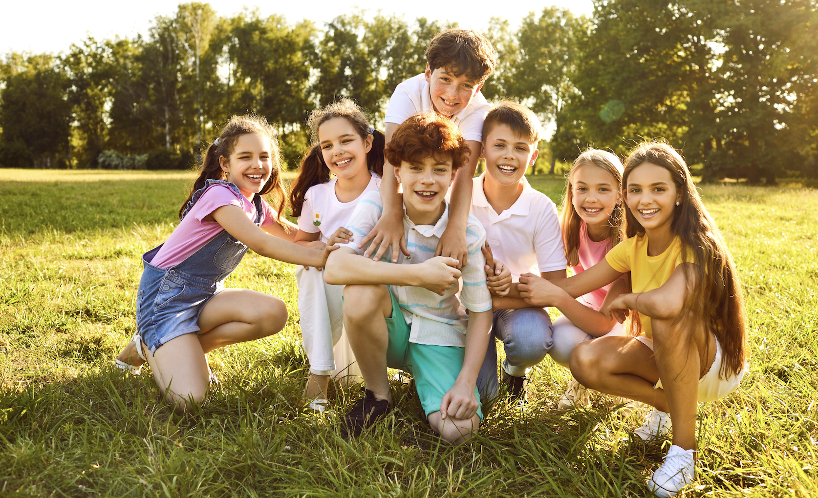 Kindergruppe auf einer Wiese, die bei schönem Wetter glücklich sind