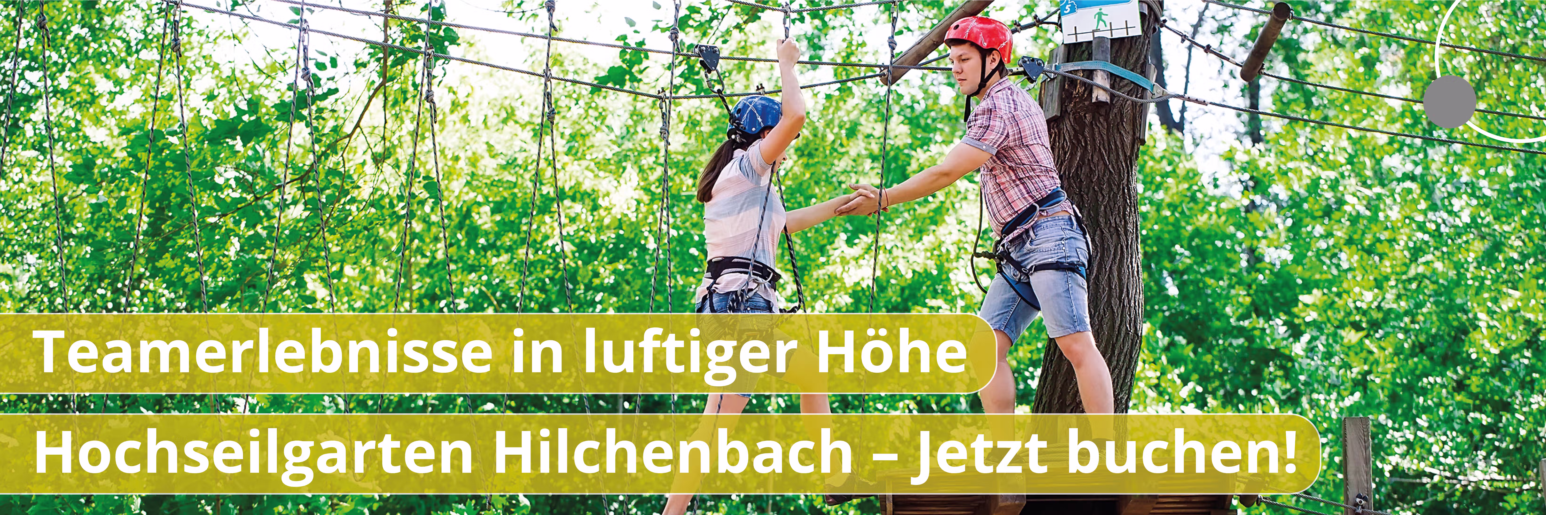 Zwei Personen mit Helmen und Klettergurten halten sich im Hochseilgarten an Händen.