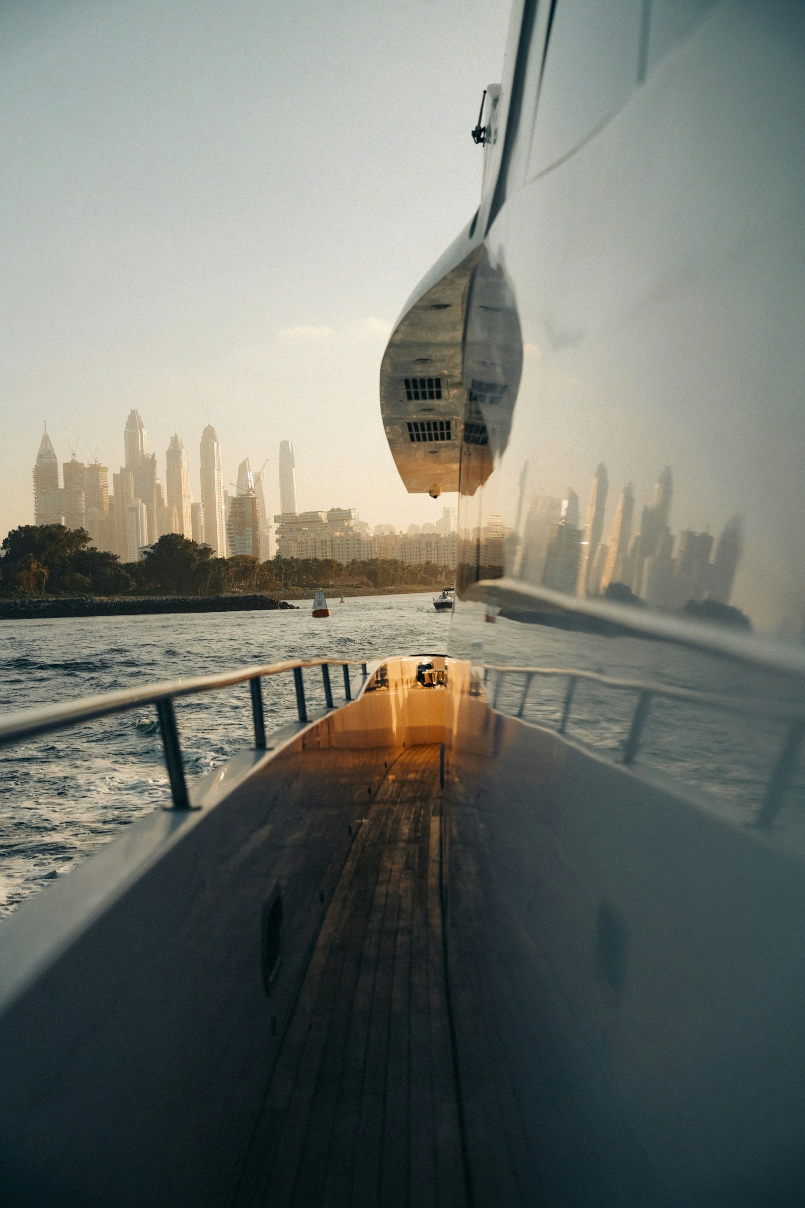 Yacht sailing past the Dubai skyline at sunset