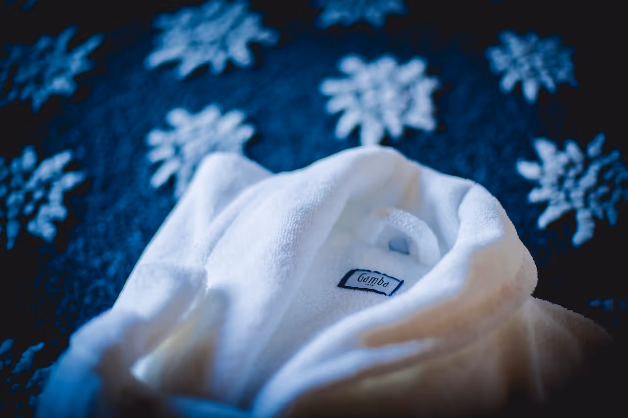 A soft white bathrobe resting on a snowflake-patterned blanket, exuding warmth and comfort.