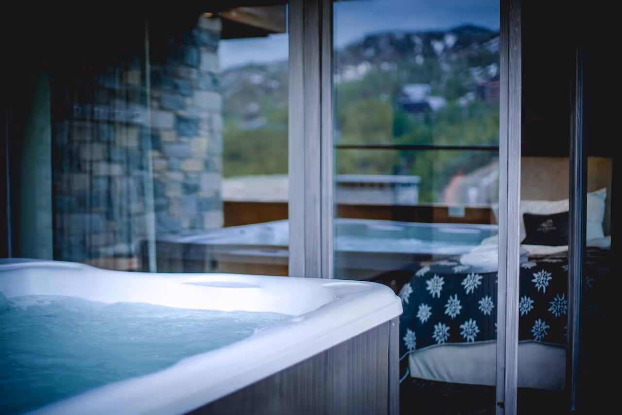 View from the hot tub to a cozy bedroom with warm wooden decor and snowflake-patterned bedding.