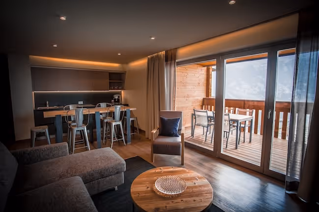Open keuken in een luxe Spa Suite met een houten bartafel en metalen stoelen, met uitzicht op een eigen balkon.