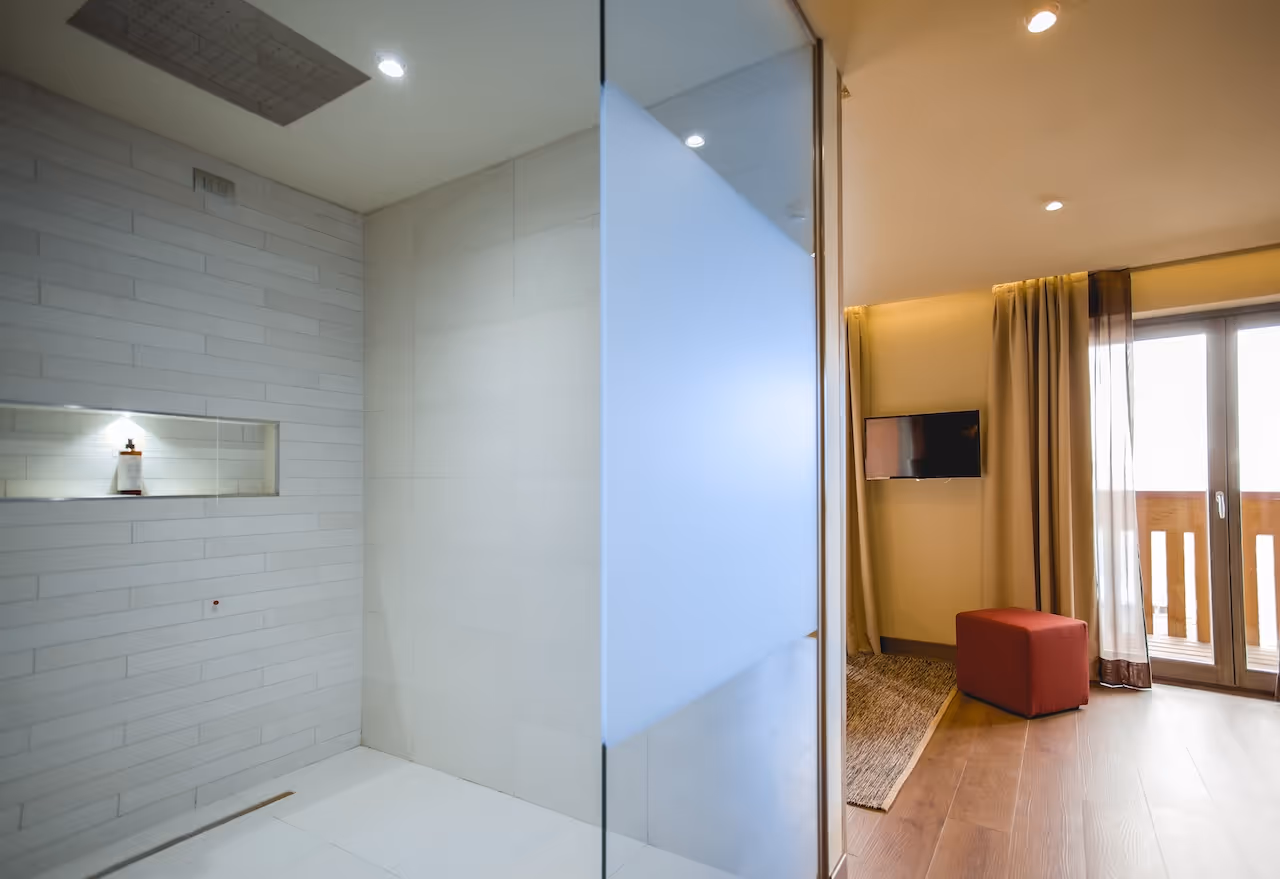 Modern bathroom with a walk-in shower, sleek white tiles, and a frosted glass partition for privacy.