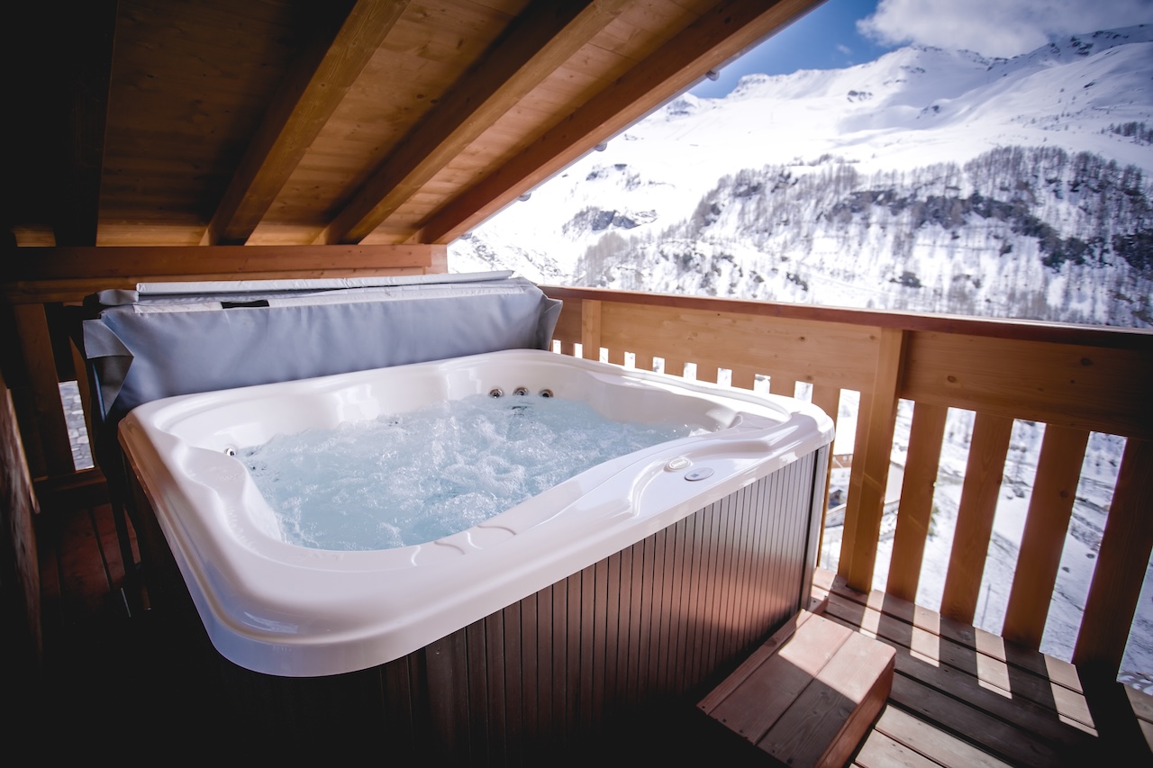 Private outdoor jacuzzi on the south-facing balcony of the Retreat Suite at La Cresta, with panoramic views of the snow-capped Alps.
