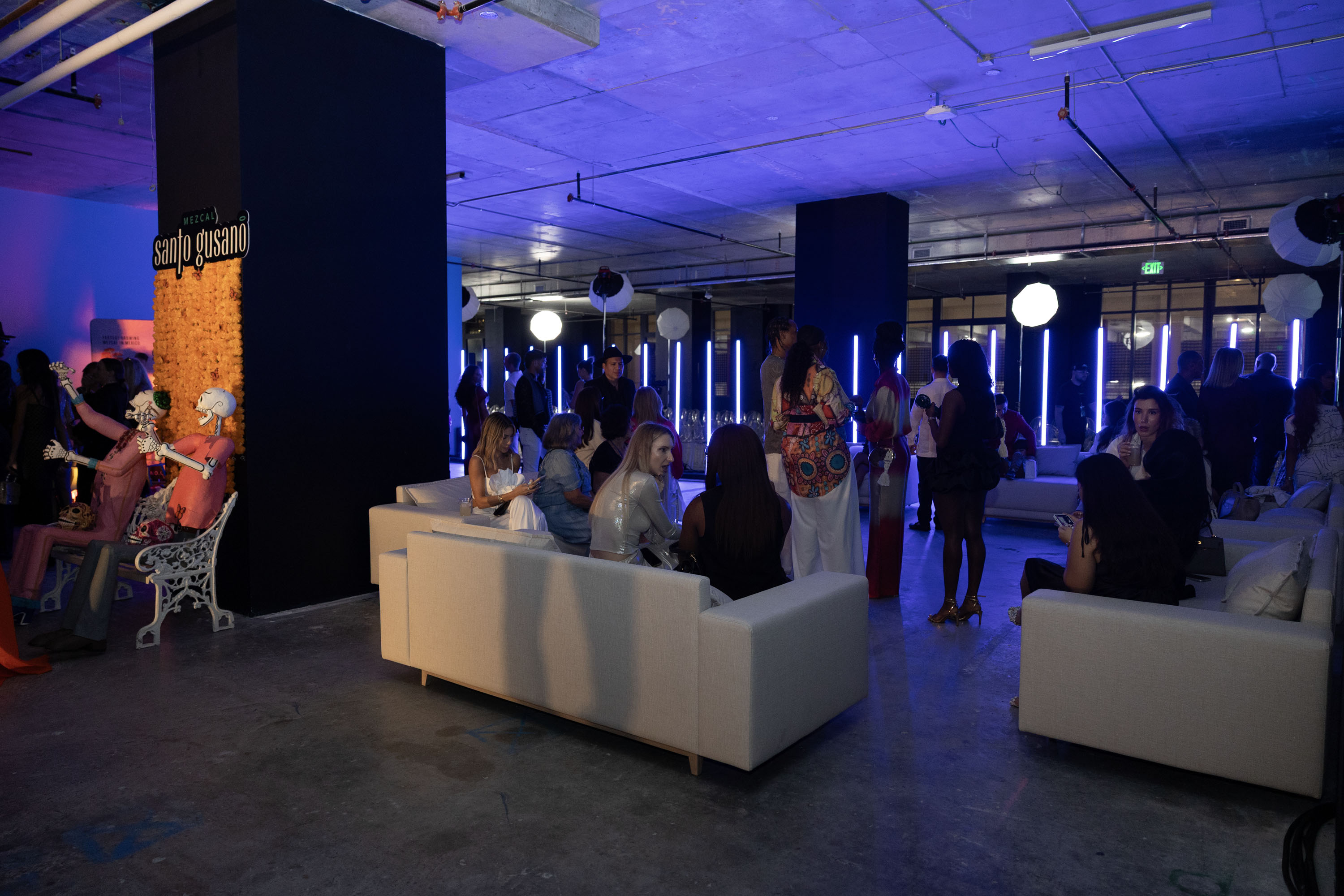 A social gathering in the exhibition center at the Gale Miami Hotel, illuminated by blue ambient light.