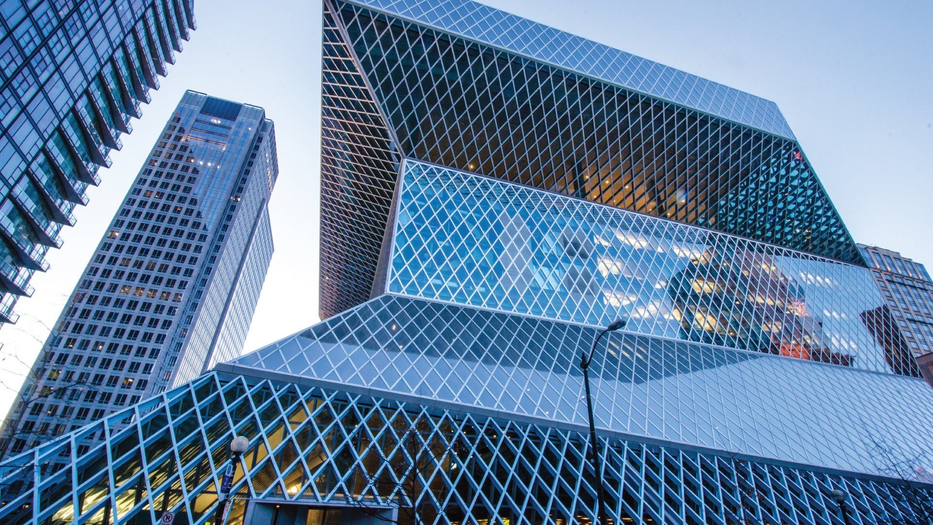 Low-angle view of modern glass buildings with crisscross lattice patterns against a clear sky.