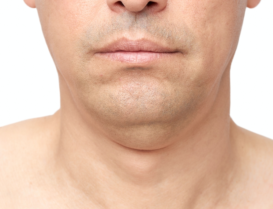 Close-up of a man's lower face showing mouth, chin, and neck with subtle facial stubble on light skin.