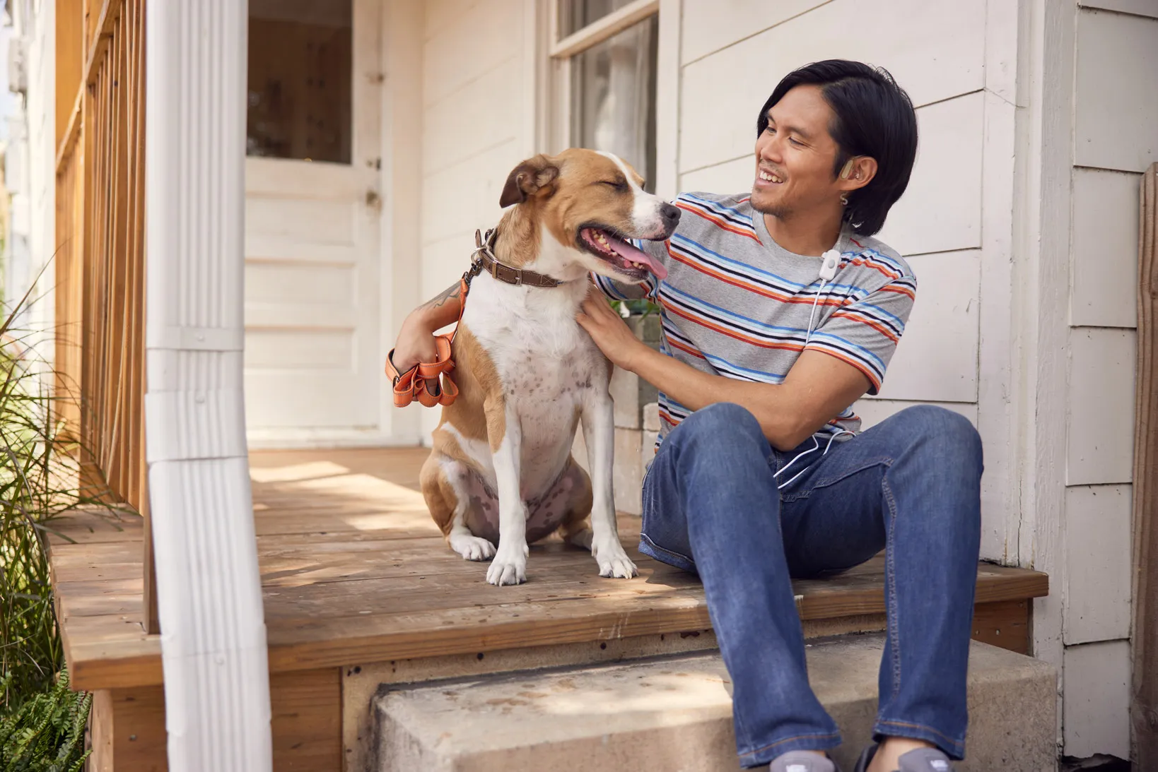 Man smiling with dog while wearing Sparrow Ascent treatment device for opioid withdrawal relief at home