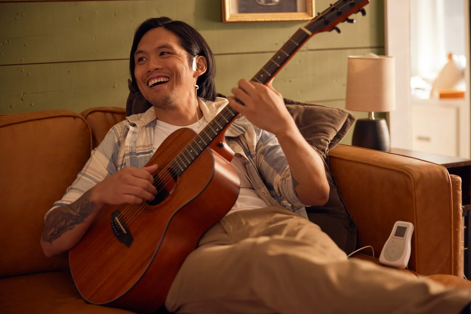 Man playing guitar while wearing Sparrow Ascent treatment device for opioid withdrawal relief at home