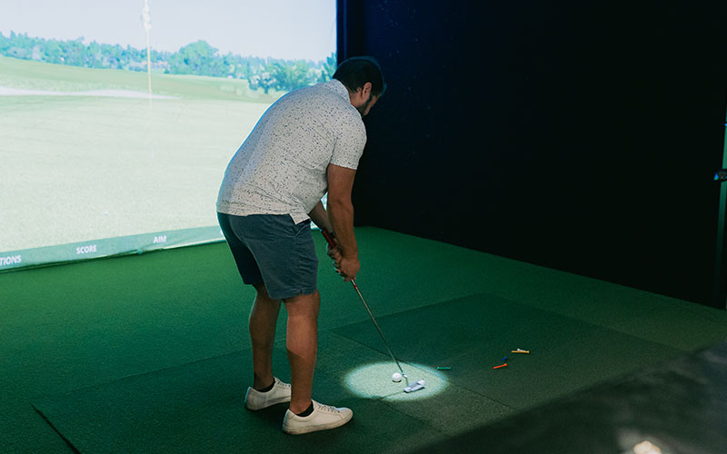 golfer set up to a tee on a golf simulator ready to putt
