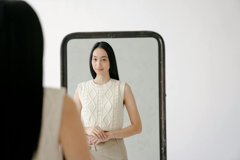 Femme se regardant dans un miroir avec douceur, illustrant l’acceptation de soi et la bienveillance envers son image.