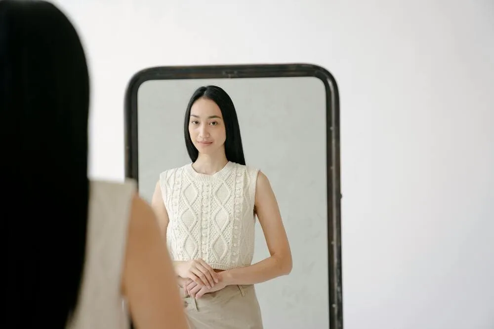 Femme se regardant dans un miroir avec douceur, illustrant l’acceptation de soi et la bienveillance envers son image.