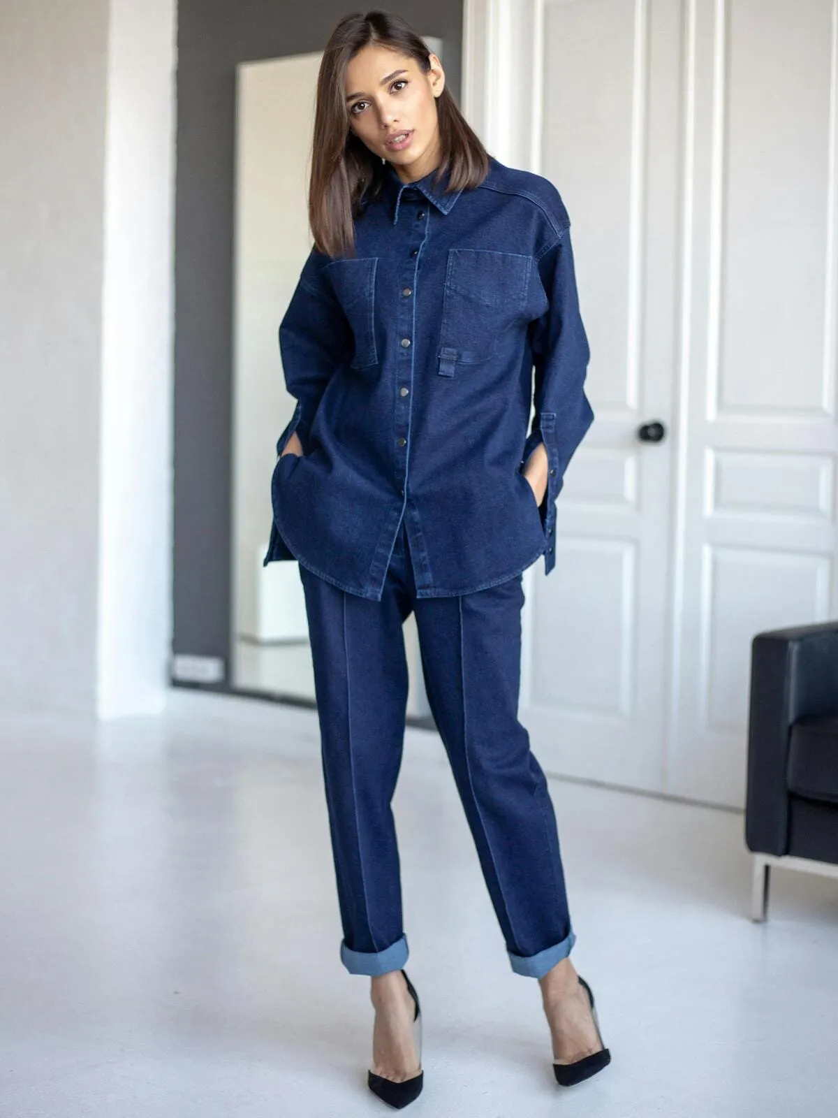 Femme chic et stylée portant une chemise en jean oversize et un jean avec une paire d'escarpins noirs