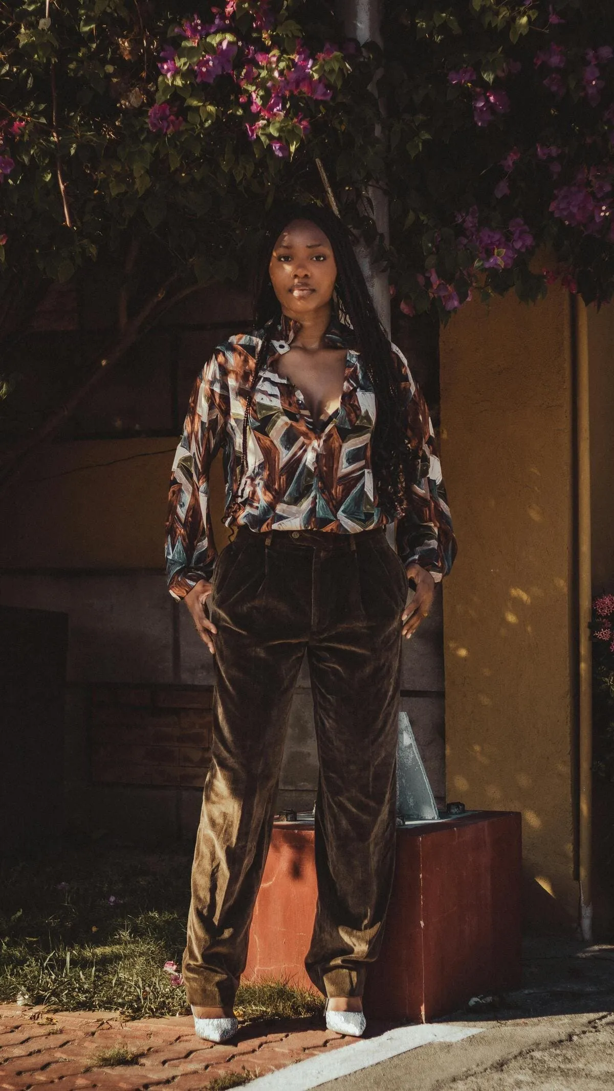 Femme avec de longues tresses portant un chemisier coloré et un pantalon kaki en velours côtelé n