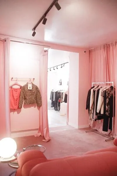Cabine d’essayage rose avec sélection de vêtements illustrant une séance de personal shopping avec Frangie à Paris.