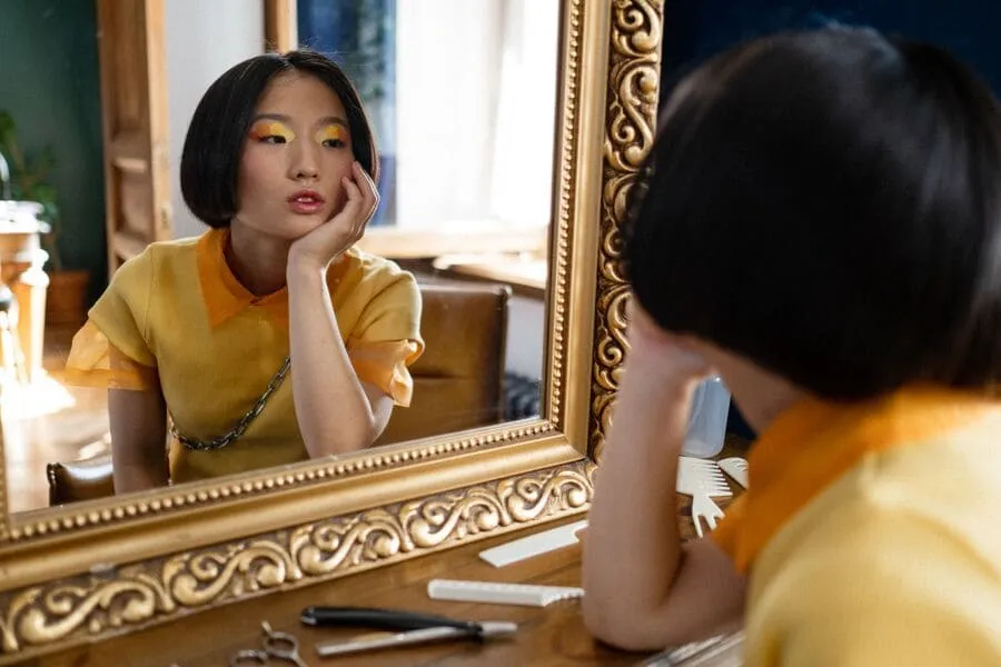 Femme face à un miroir portant des couleurs chaudes, illustrant une séance de colorimétrie avec Frangie à Paris.