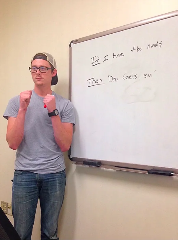 Old photo of one of the founders of of Peartree Web Development with glasses and backwards cap standing with fists raised near whiteboard with handwritten phrase.