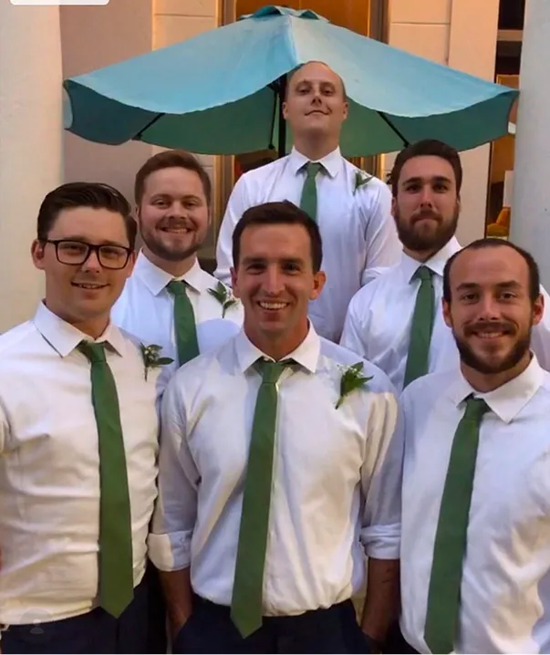 Old photo of the founders of Peartree in a wedding party, posing together with white shirts and green ties.