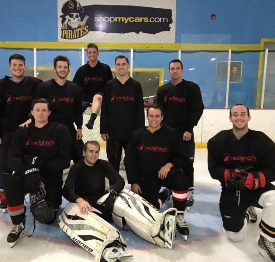 Founders of Peartree in a hockey team photo in black jerseys posing on ice rink