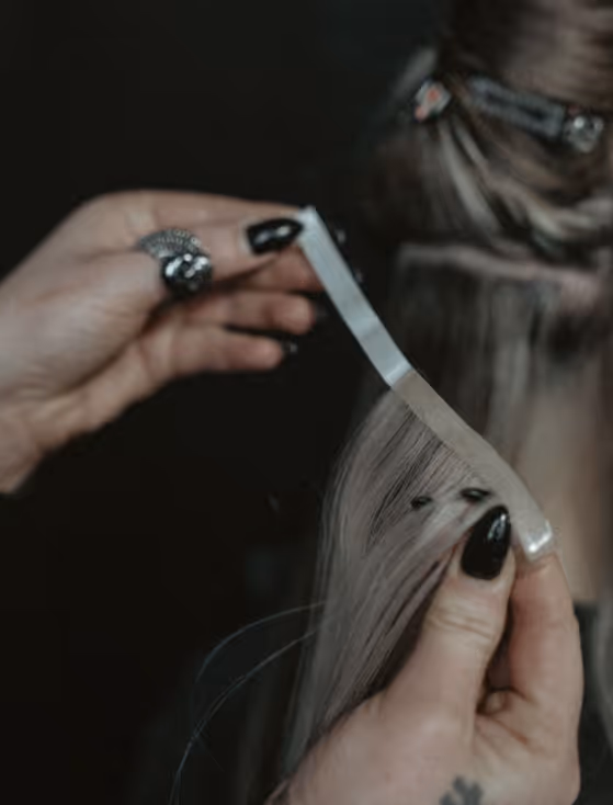 Närbild på när en frisör sätter in hair extensions på en kund