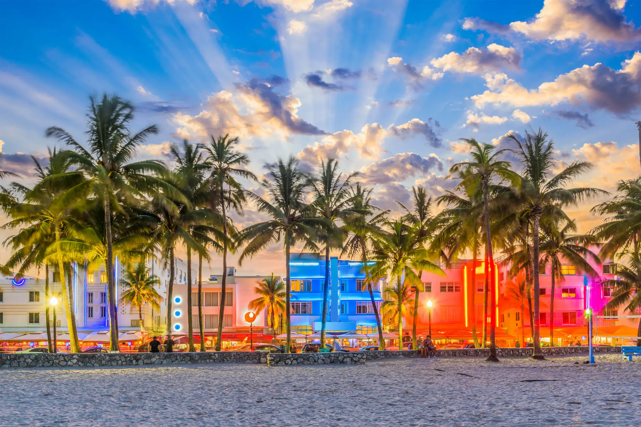 A beach with palm trees and a building in the background.