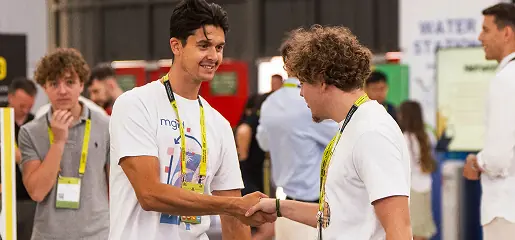 Two men shaking hands in front of a crowd of people.