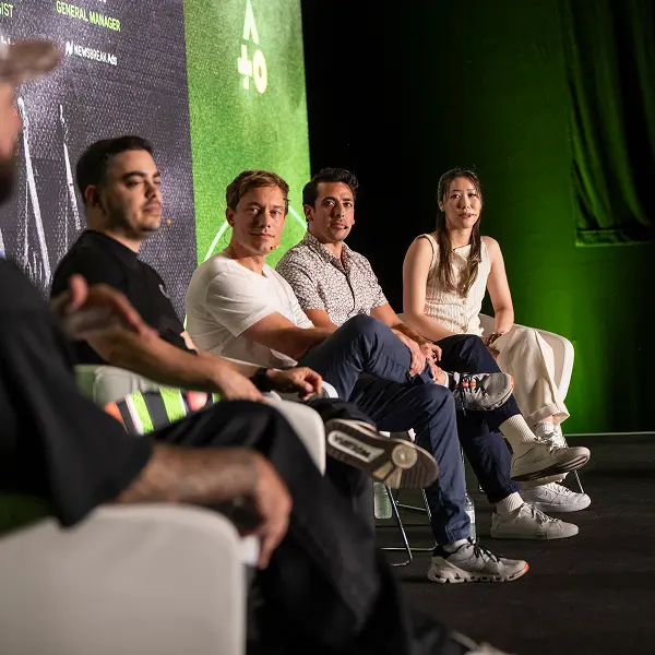 A group of people sitting in chairs in front of a green wall.