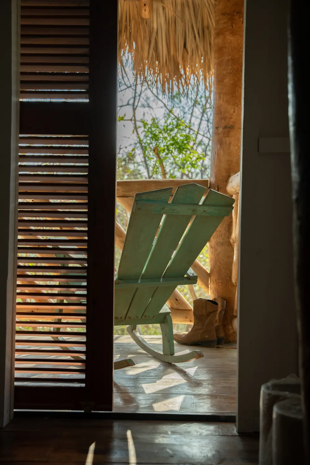 An open door with a rocking chair and cowboy boots in view. 