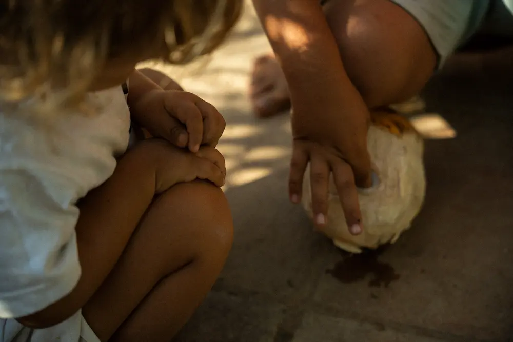 Two children enjoying a coconut together. 
