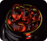 Close-up of a bottle filled with shiny red gel capsules, possibly supplements or vitamins.