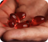 Close-up of a hand holding several red gel capsules or pills.