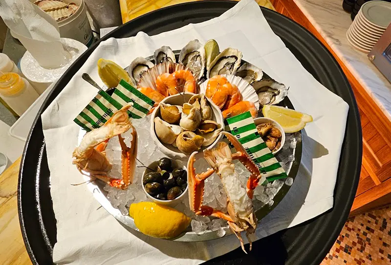 Plateau de fruits de mer avec huîtres, crevettes, bulots, escargots de mer, crabes et quartiers de citron sur un lit de glace.