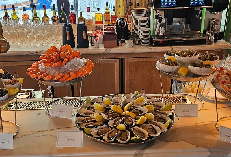 Plateaux de fruits de mer avec crevettes, huîtres garnies de quartiers de citron, et bulots présentés sur un comptoir de restaurant.