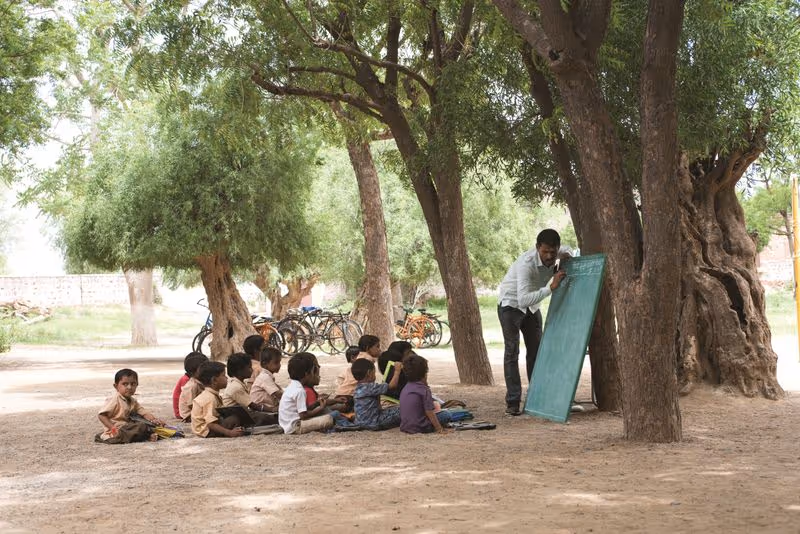 A group of children in the school sitting on the ground