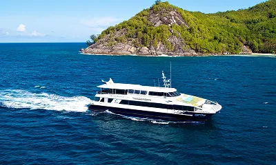 Cat Cocos ferry sailing past a lush green island in Seychelles, offering fast and scenic inter-island transfers with SeyFerry.