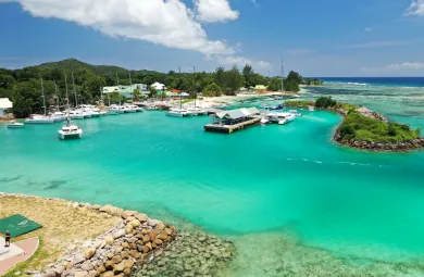 Scenic view of the ferry jetty and marina on La Digue island, Seychelles, with turquoise waters, moored catamarans, and lush tropical surroundings—arrival point for Cat Rose and Cat Cocos ferries.