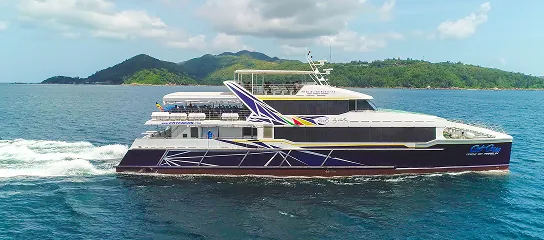Cat Cocos ferry sailing near a lush green island in Seychelles, showing its sleek design and multiple passenger decks.